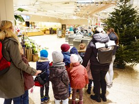 Kinder schmücken einen Weihnachtsbaum im Supermarkt.