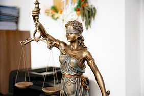 Bild einer bronzenen Statue der Justitia in einem Büro.