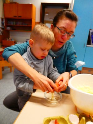 Kind mit Erzieher:in beim backen