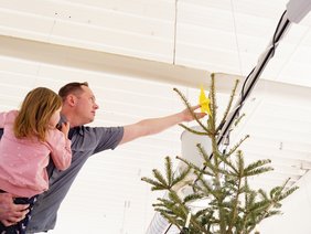 Kinder schmücken einen Weihnachtsbaum im Supermarkt.