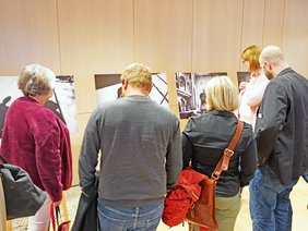 Besuchende betrachten die ausgestellten Fotografien.
