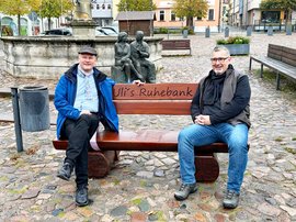 Ulrich Schulte und Alexander Brodführer sitzen auf der Bank mit der Aufschrift "Uli's Ruhebank".