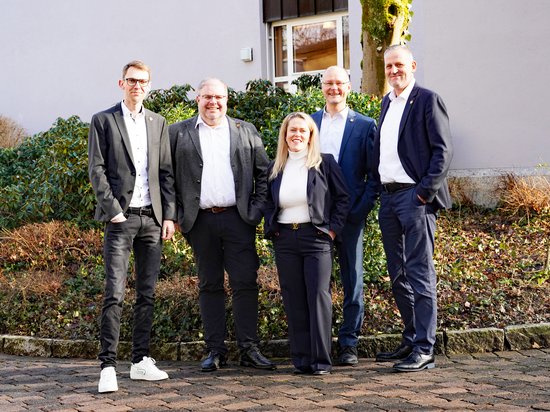Gruppenbild des Verwaltungsvorstands, draußen vor dem Ratstrakt, vor grünen Büschen, alle lächeln.