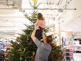 Kinder schmücken einen Weihnachtsbaum im Supermarkt.