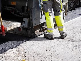 Eindrücke vom Aufbringen der Fahrbahndecke auf der L561 Herscheider Straße am 30. Mai 2025, mit Baggern, Thermomulden, LKW, Walzen und Arbeitenden.