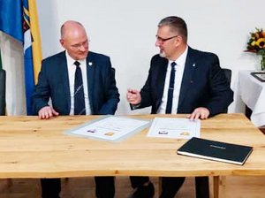 Die Bürgermeister Ulrich Schulte und Alexander Brodführer unterzeichnen an einem Tisch die Urkunde zur Erneuerung der Städtepartnerschaft.