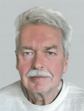 Portraitfoto von Peterdirk Schweighöfer, kürzere graue Haare, grauer Oberlippenbart, leicht lächelnd.