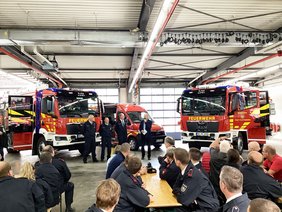 Drei neue Feuerwehrfahrzeuge in der Halle, davor die Akteure von Feuerwehr und Stadtverwaltung.