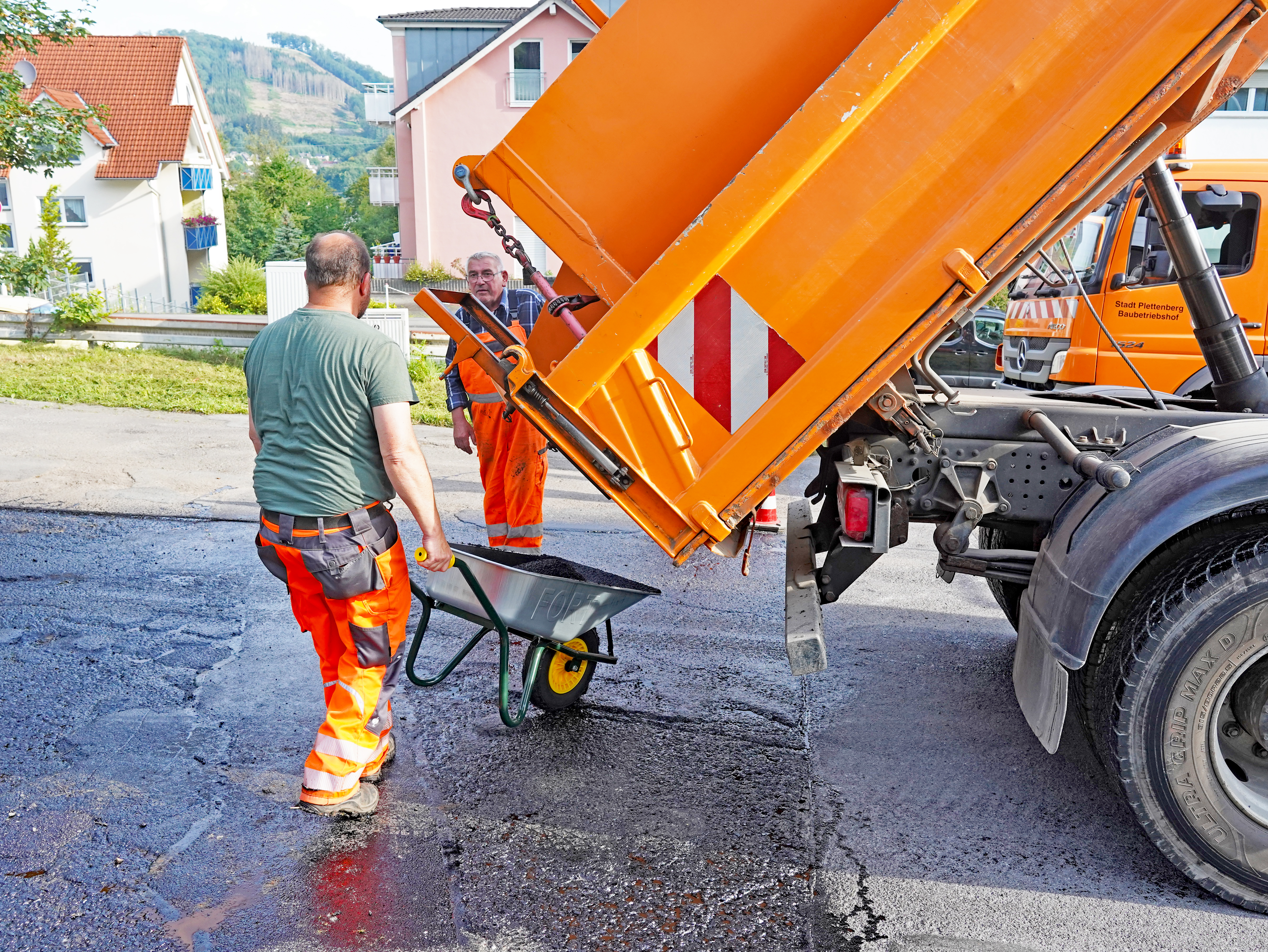 Der Asphaltbeton wird aus dem LKW in die Schubkarre geschüttet. (Bild: Stadt Plettenberg)