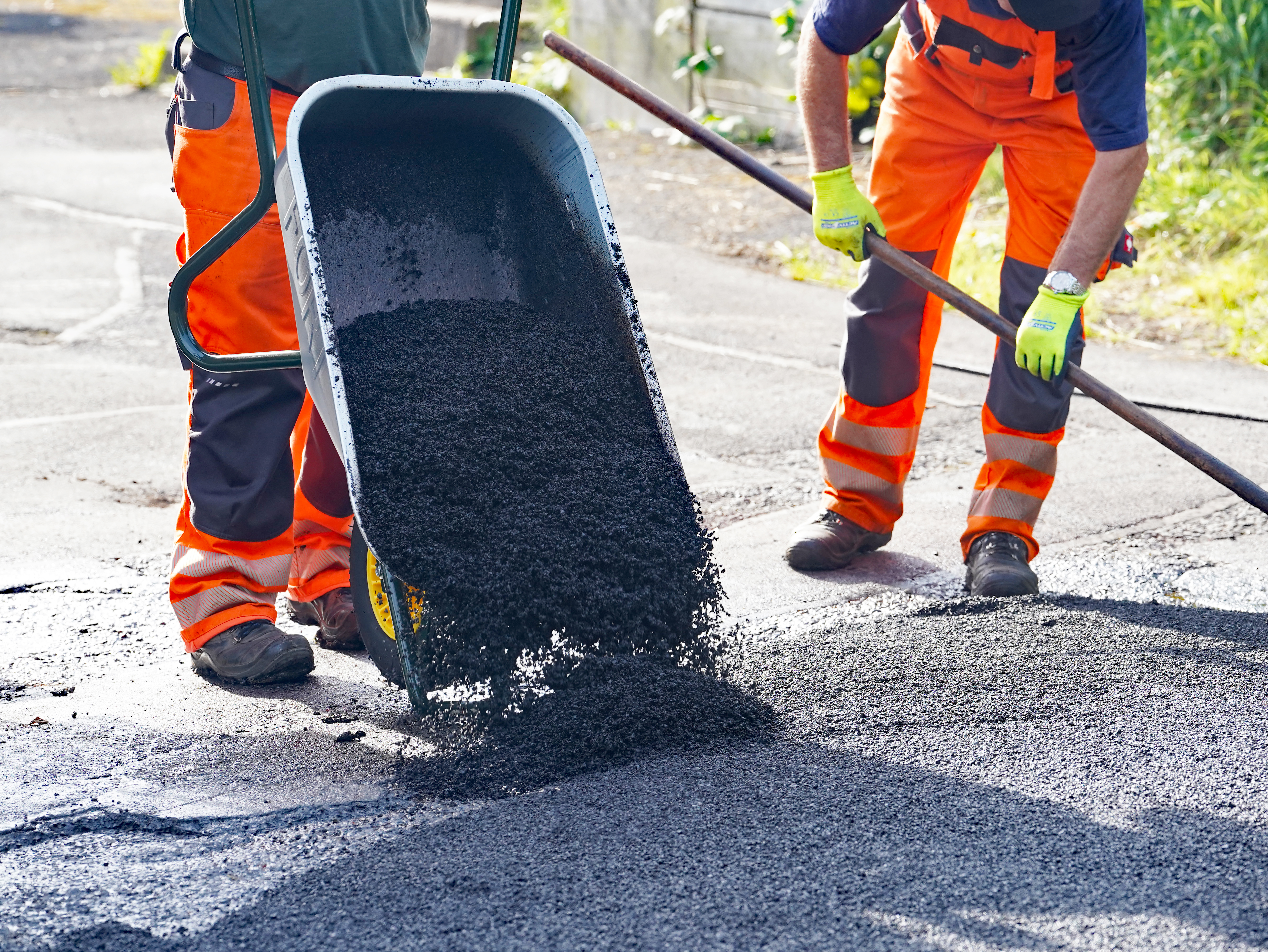 Asphaltbeton wird aus der Schubkarre gekippt. (Bild: Stadt Plettenberg)