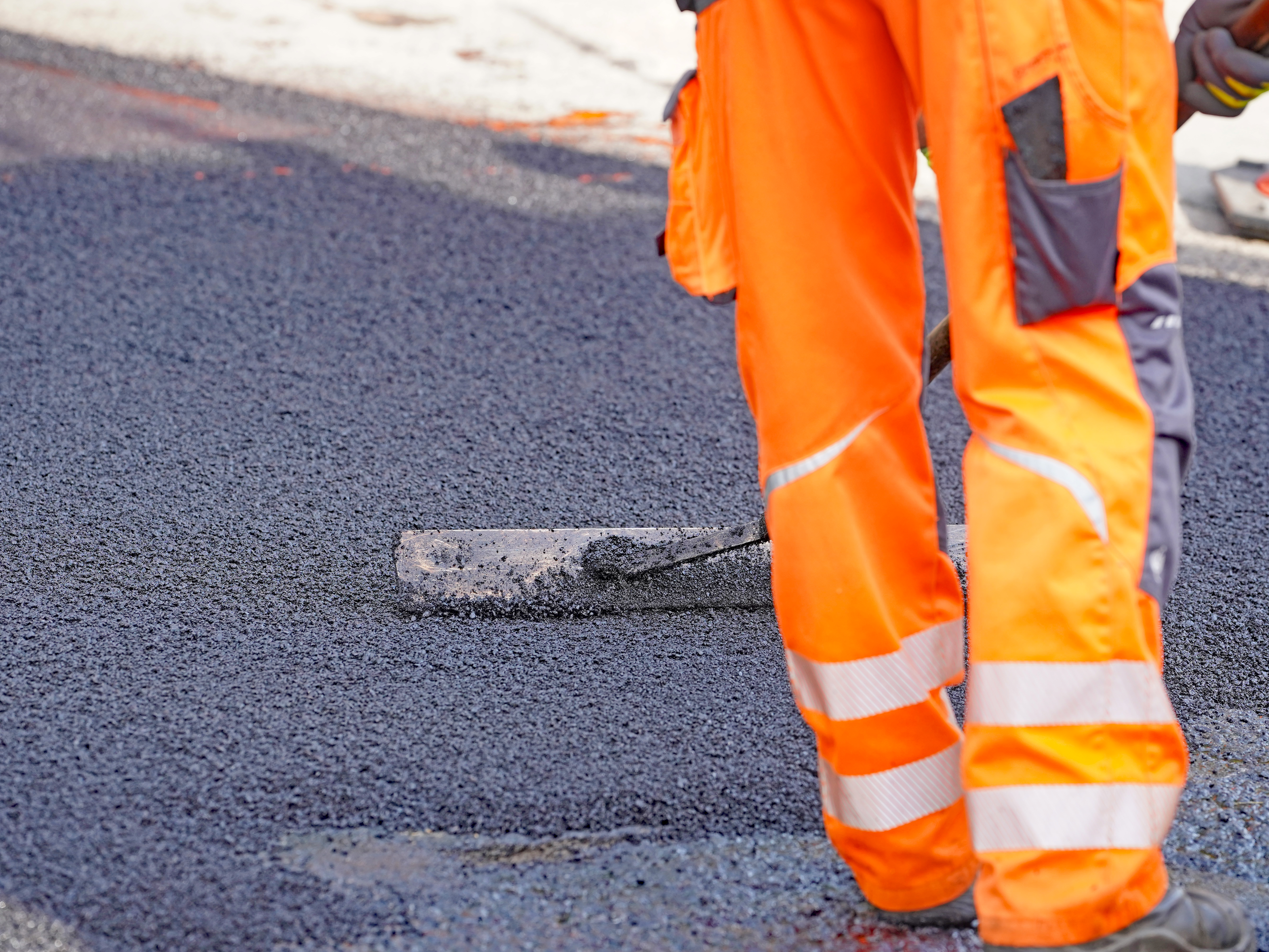 Nahaufnahme des Verteilens des Asphaltbetons mit einem Schieber. (Bild: Stadt Plettenberg)