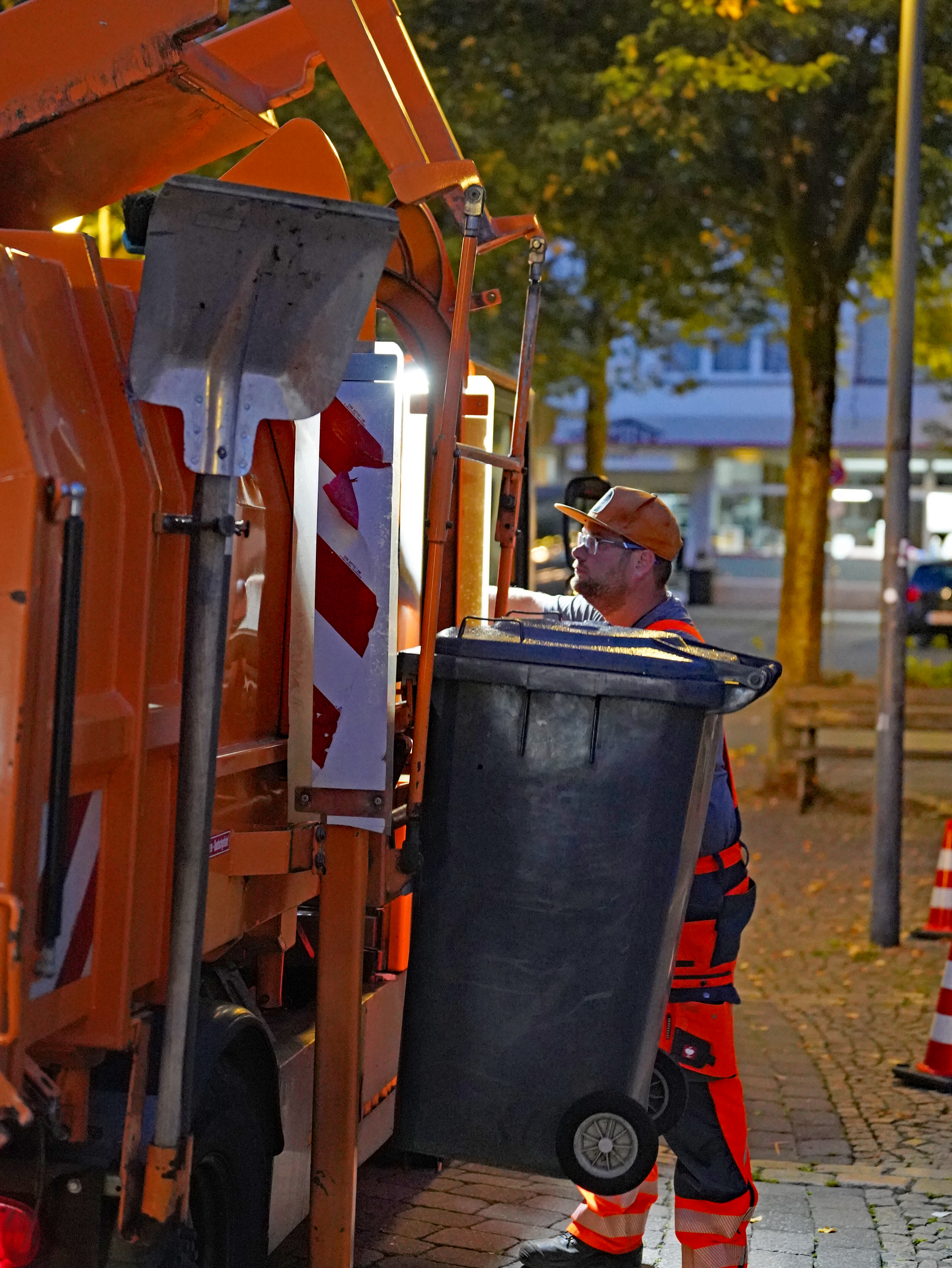 Christopher Schmidt lässt an der Seite eine Tonne am Fahrzeug zum Entleeren hochfahren.