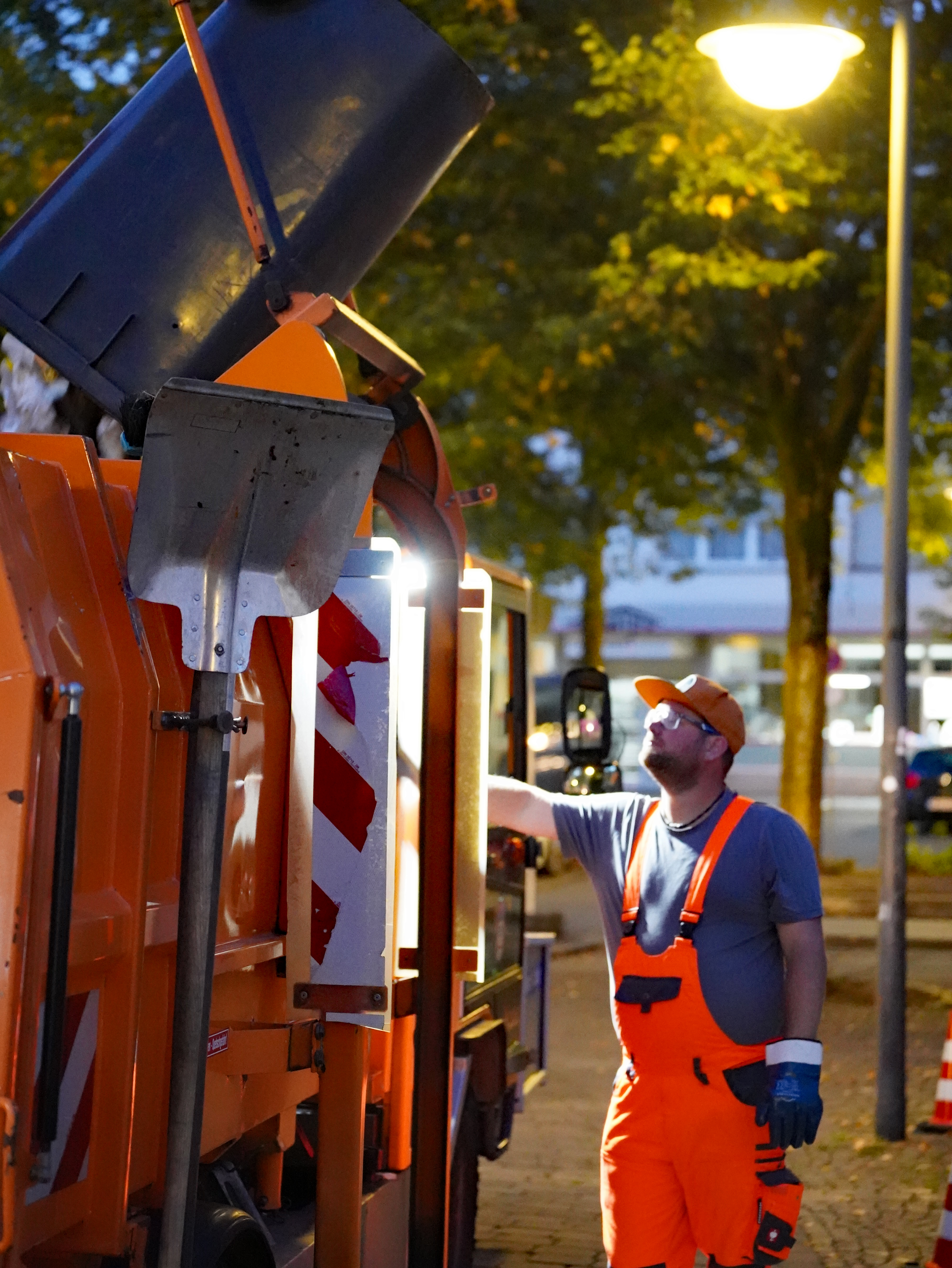 Die Mülltonne wird hydraulisch über das Fahrzeug gehoben und kopfüber entleert.